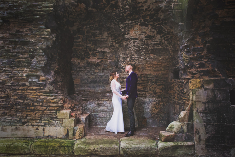 A newlywed bride and groom stood in a heart shaped alcove among the ruins of Newark Castle